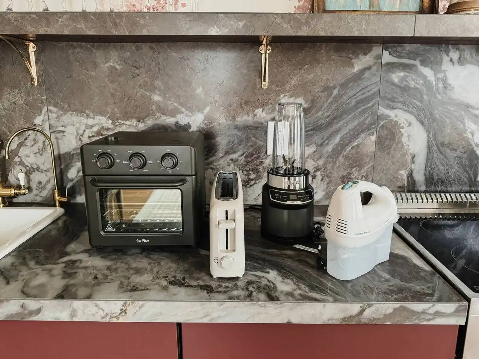 Countertop appliances including an oven, toaster, blender, and vacuum cleaner on a marble surface