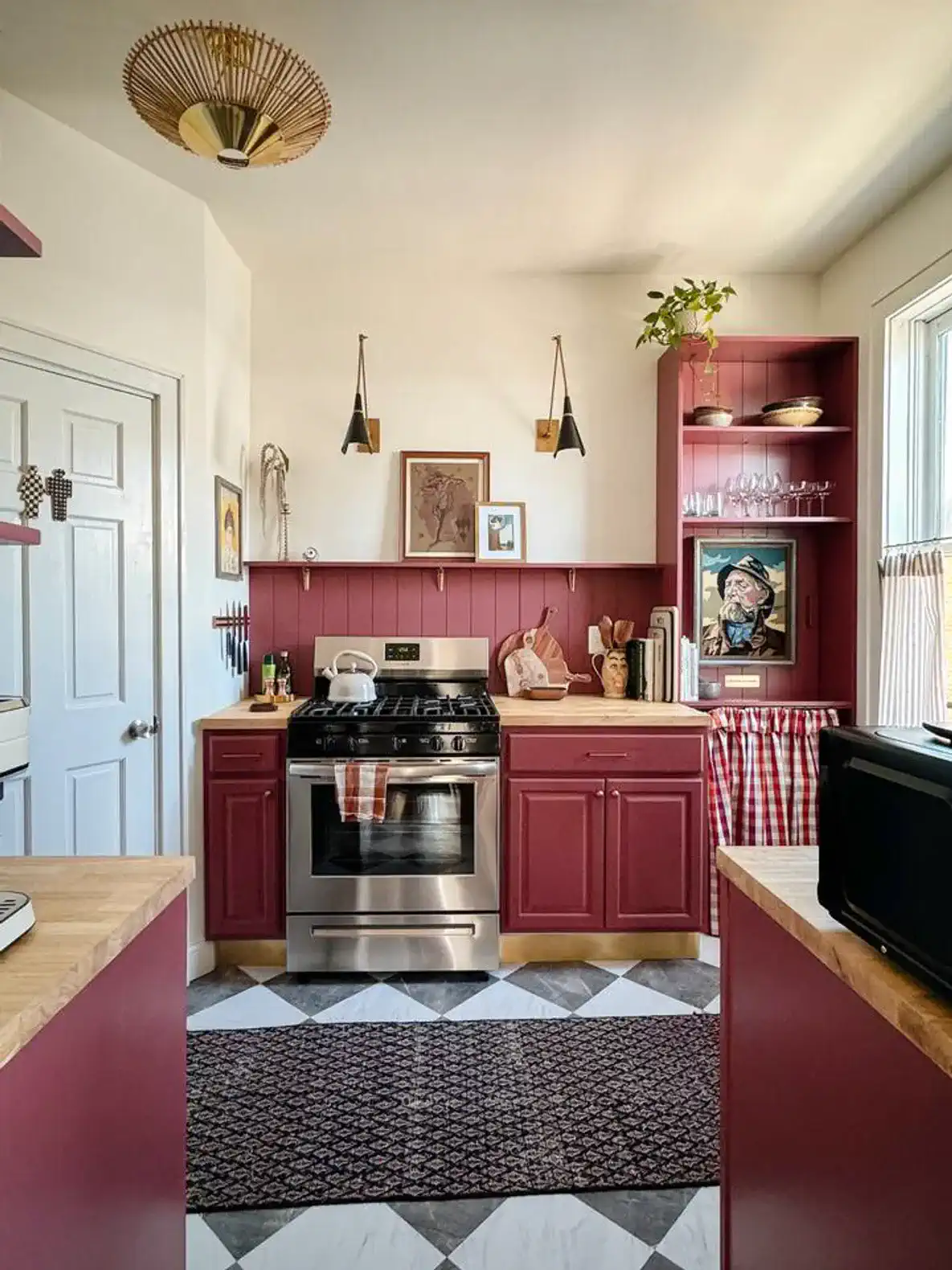 Charming kitchen with maroon cabinets, stainless steel appliances, and patterned floor tiles