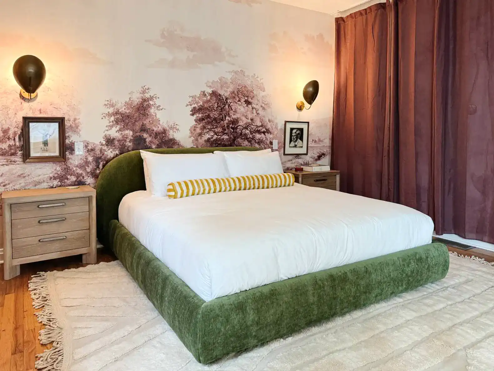 Stylish master bedroom with green upholstered bed and artistic wallpaper