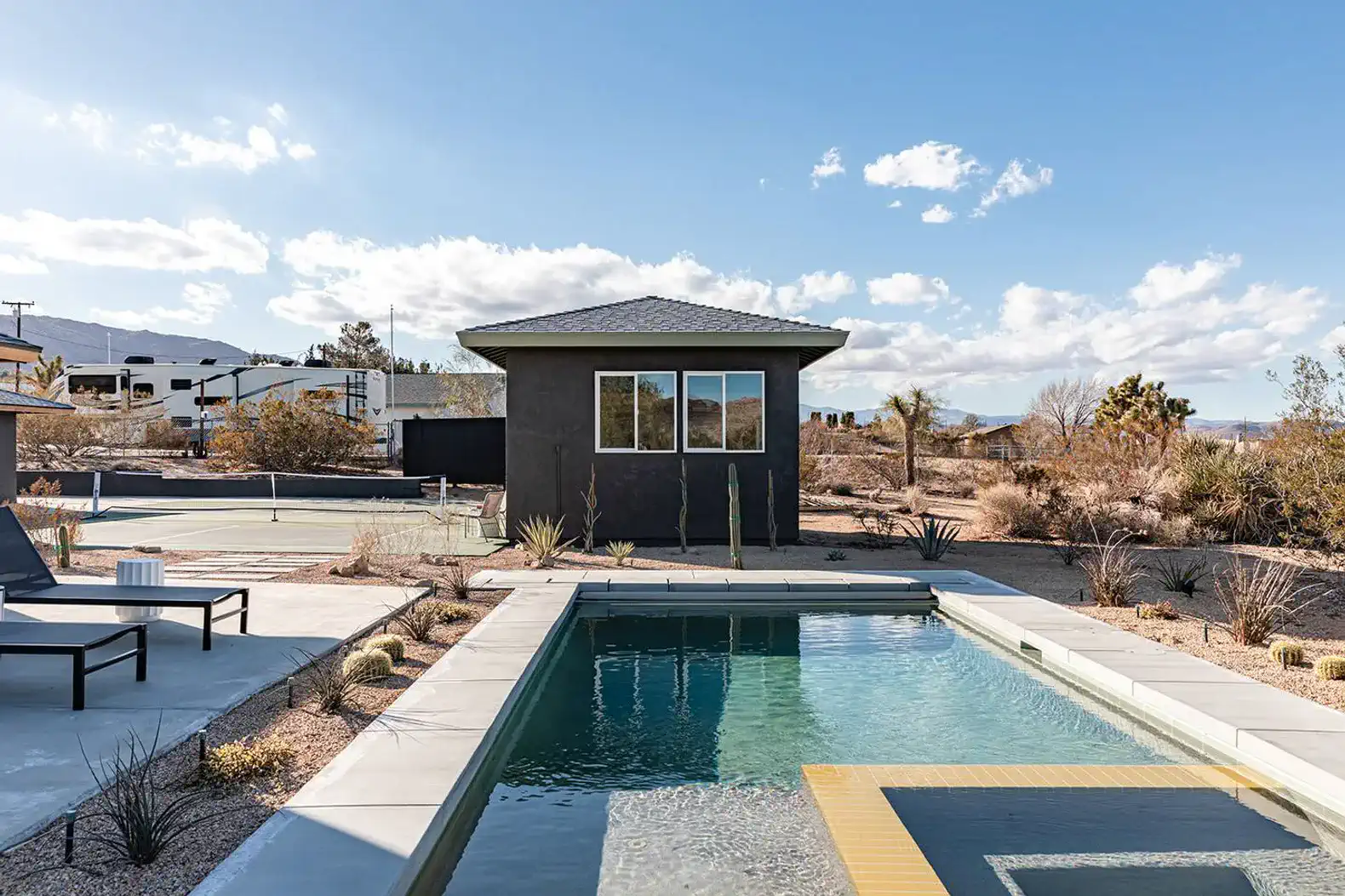 Modern pool area with desert landscaping and a view of the nearby tennis courts