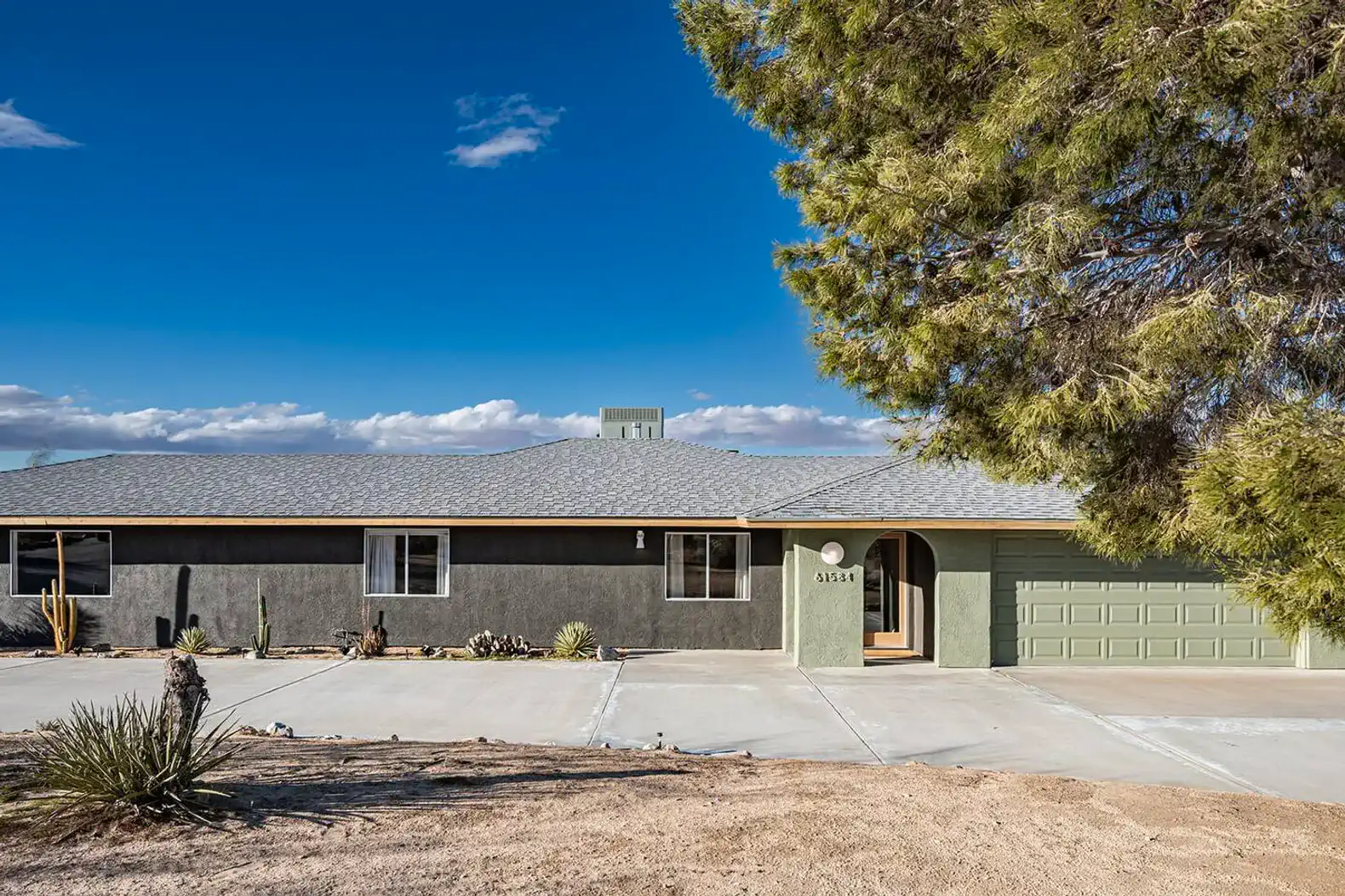 Spacious desert home with a gray exterior and a large driveway
