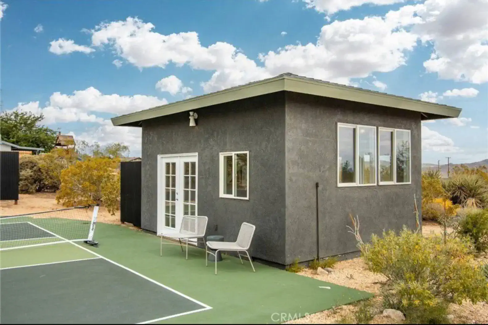 Modern exterior of a vacation rental with a tennis court and desert landscaping