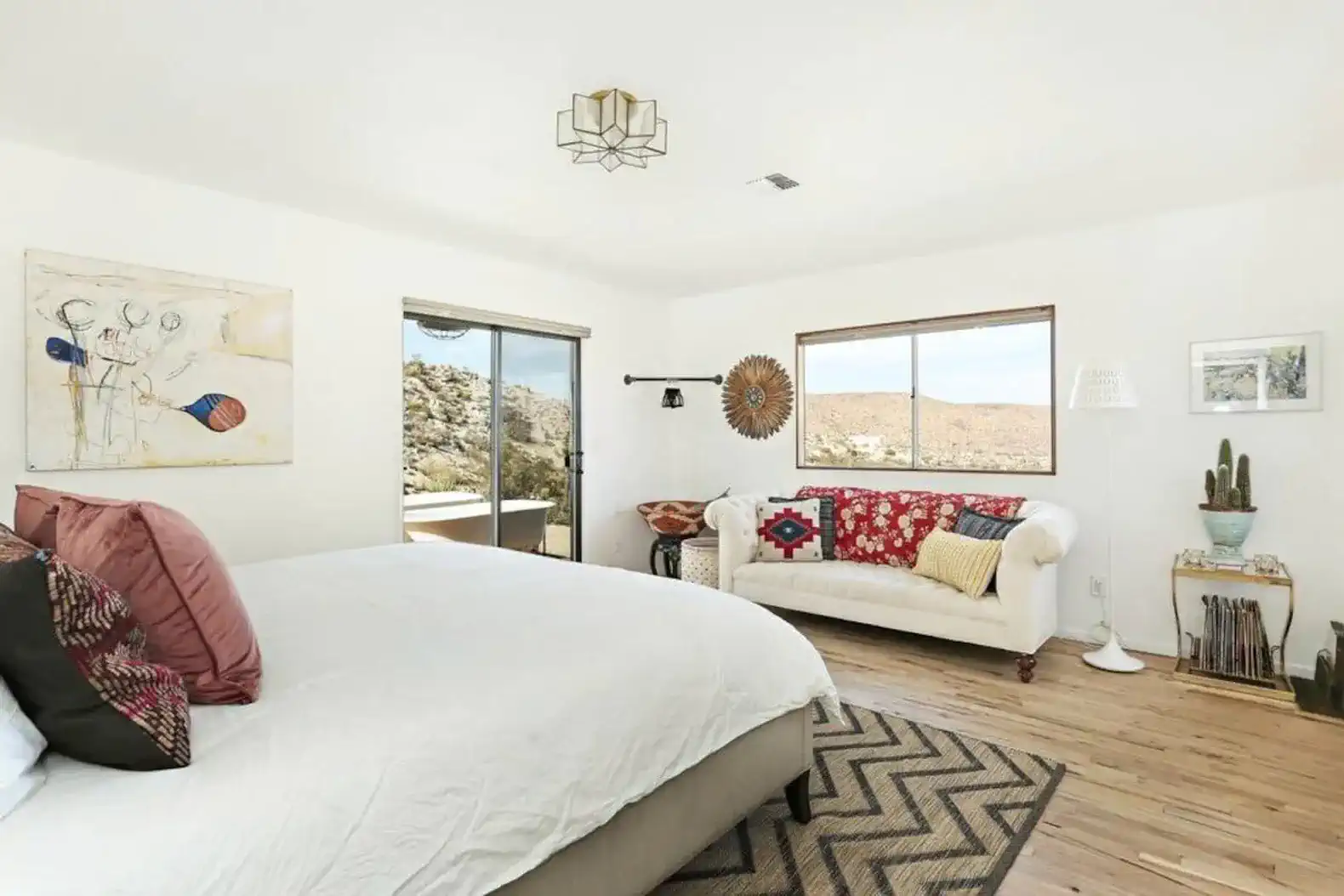 Bright master bedroom with large windows and cozy seating area