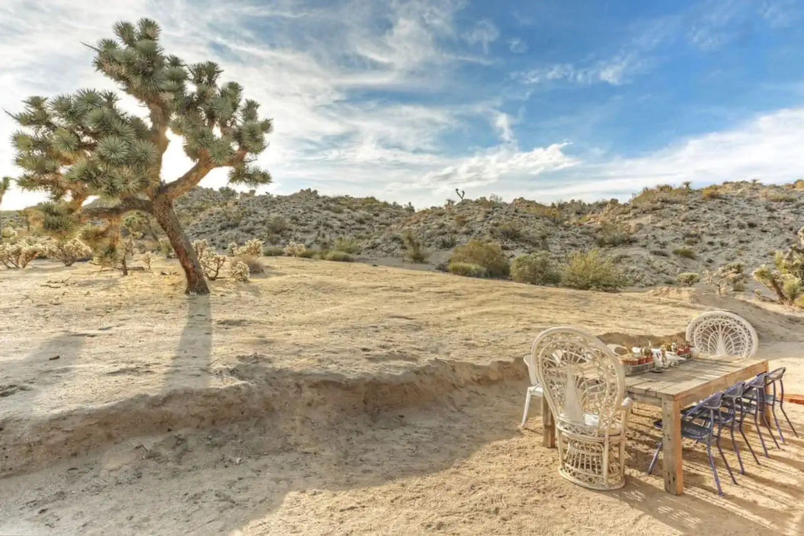 Outdoor dining area with rustic table and chairs surrounded by desert landscape