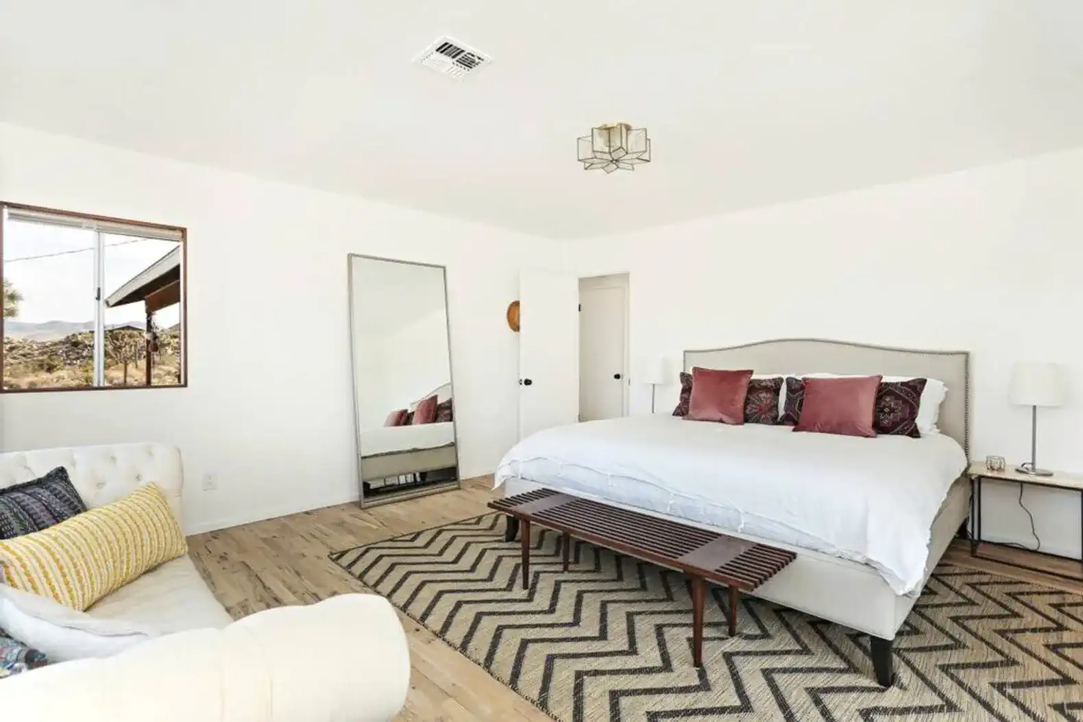 Spacious master bedroom with a large bed, seating area, and natural light