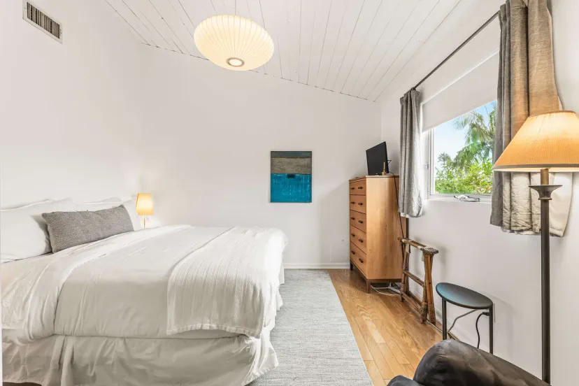 Chambre d'amis avec lit King, Smart TV, commode et fauteuil de massage de luxe.