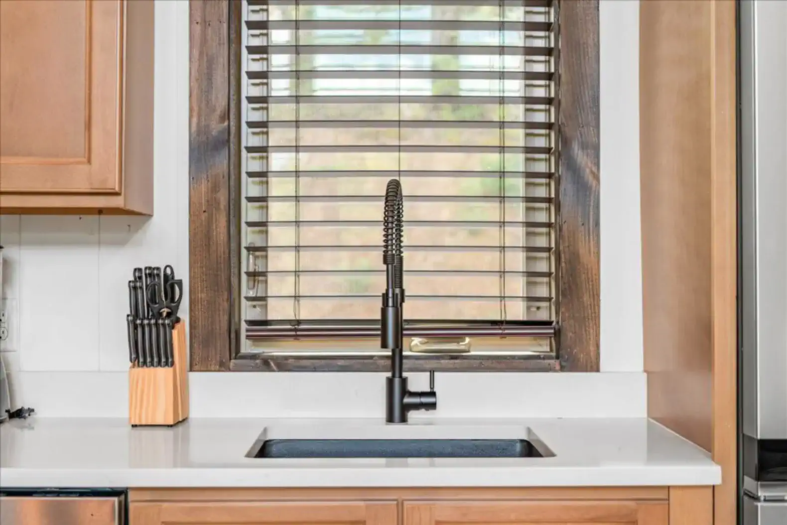 Modern kitchen sink with stylish faucet and wooden blinds