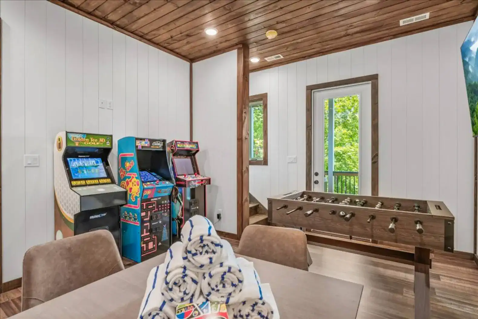 Game room featuring arcade machines and foosball table with a view of the outdoors