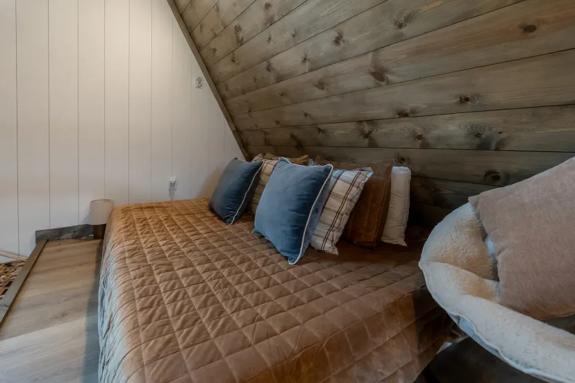 Gemütliches rustikales Schlafzimmer mit holzverkleidetem Decke und plüschigen Bettwaren