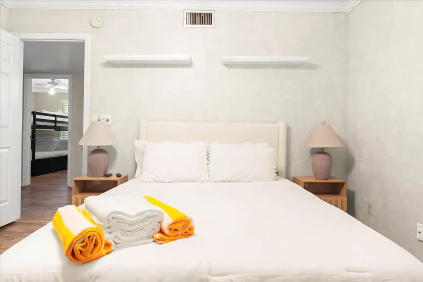 Cozy master bedroom with a queen bed and fresh linens, featuring soft lighting and a view of the bunk room