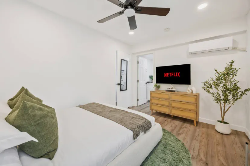 Quarto aconchegante com uma cama queen, TV e planta decorativa