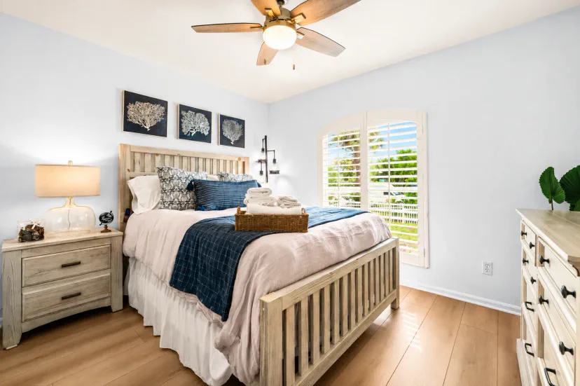 A bright and peaceful coastal bedroom with layered, comfortable bedding, warm natural textures and beautiful Florida sunshine, creating an inviting retreat for a restful night after a day of Naples adventures.