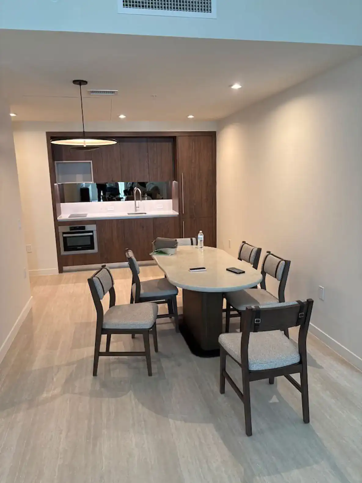 Modern dining area with a round table and six chairs near a sleek kitchen