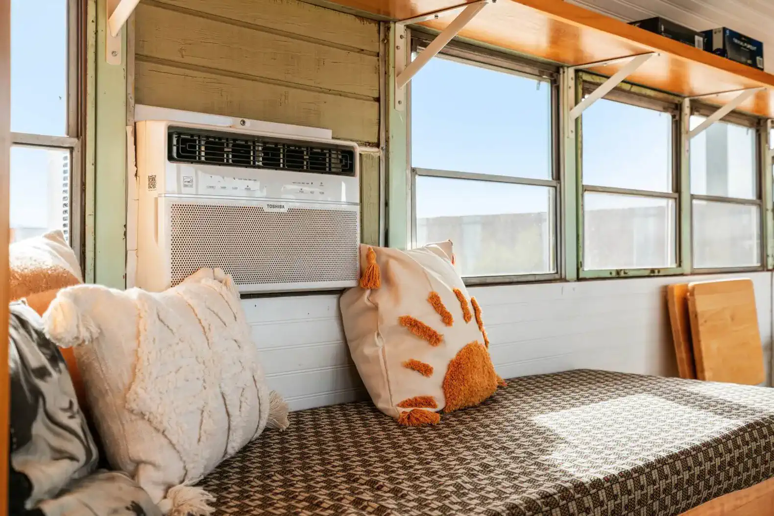 Cozy seating area with decorative pillows and air conditioning unit