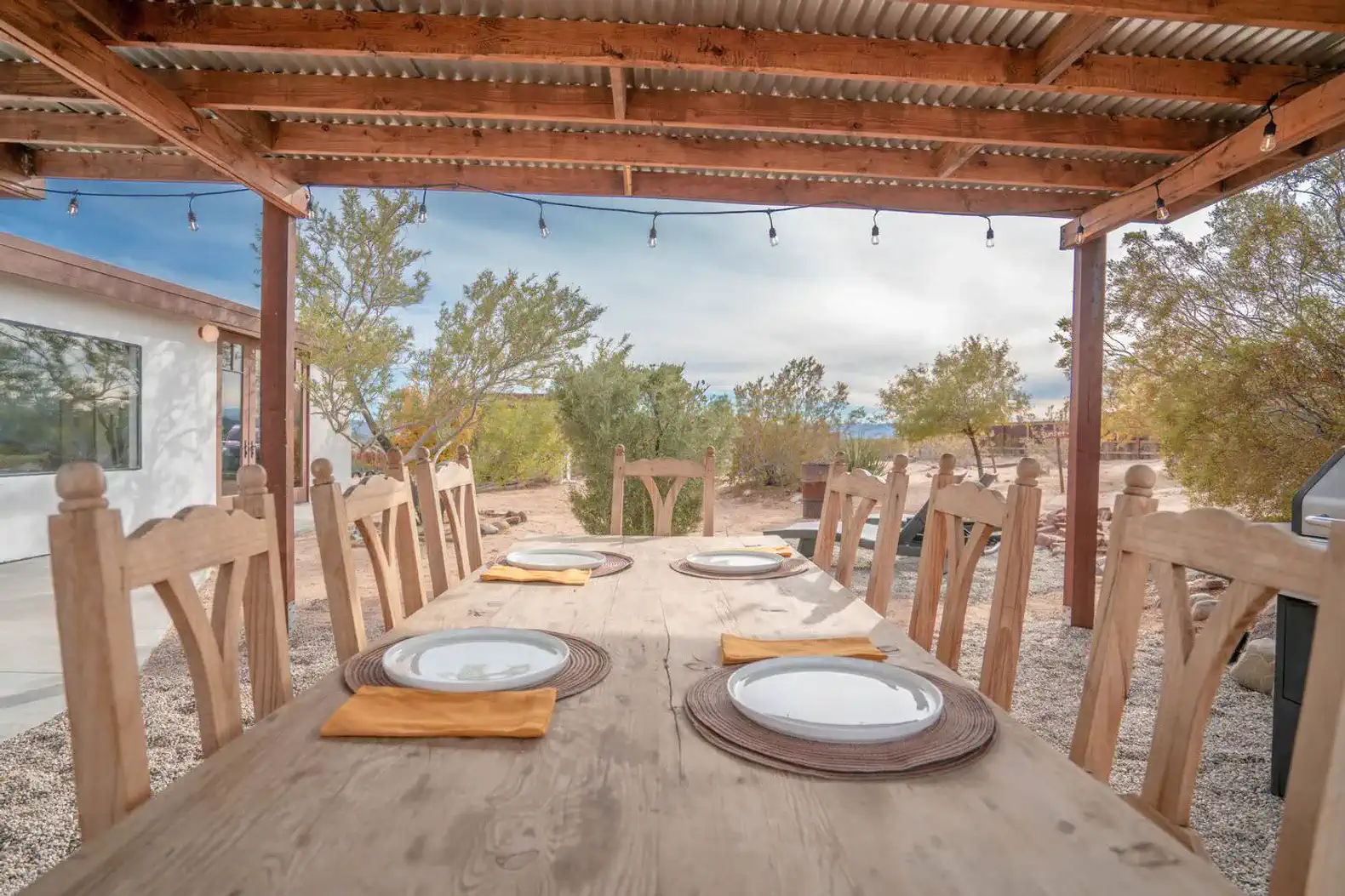 Rustic outdoor dining area with wooden table and chairs under a covered patio
