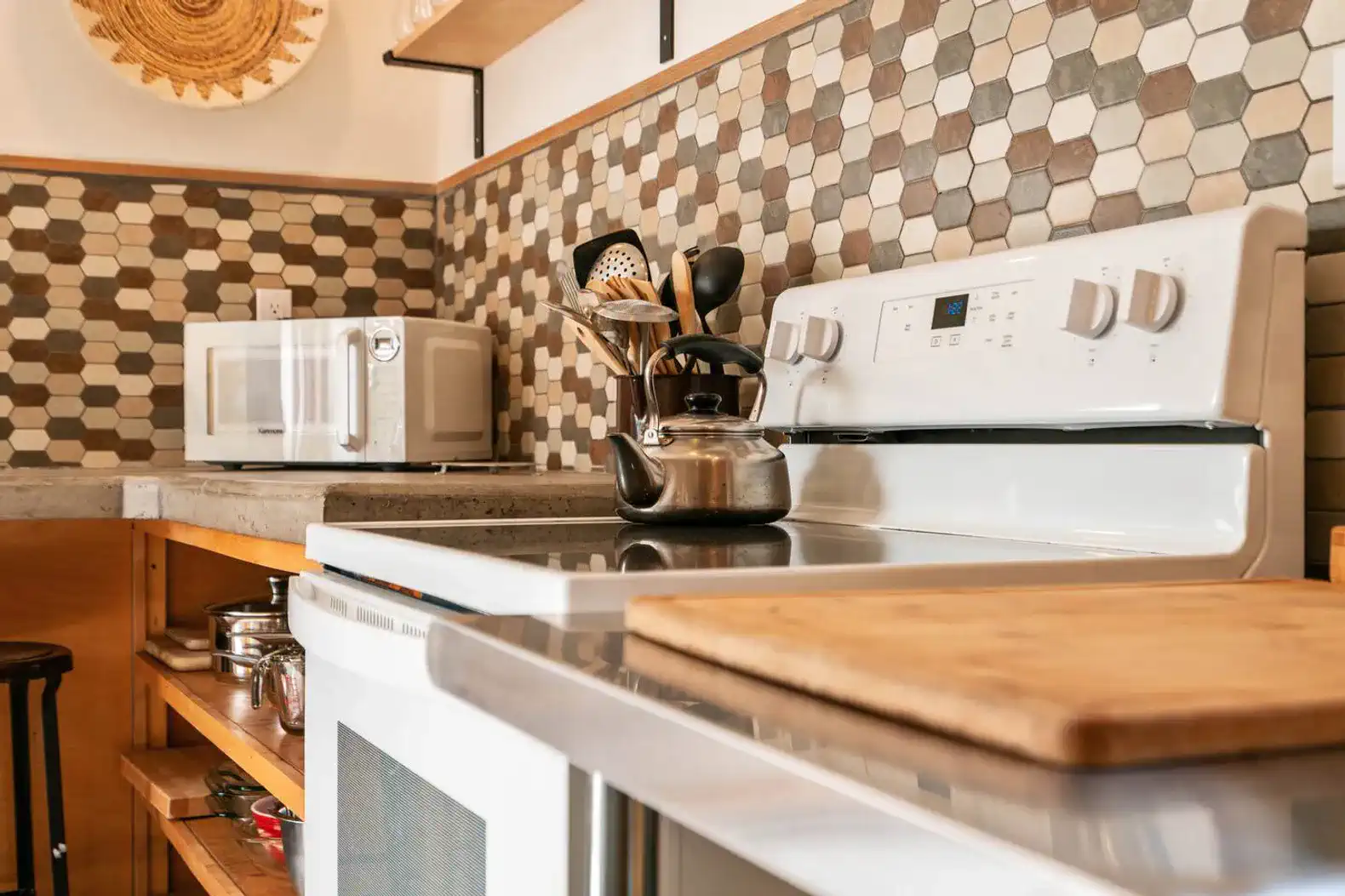 Modern kitchen with hexagonal tile backsplash, stove, and microwave
