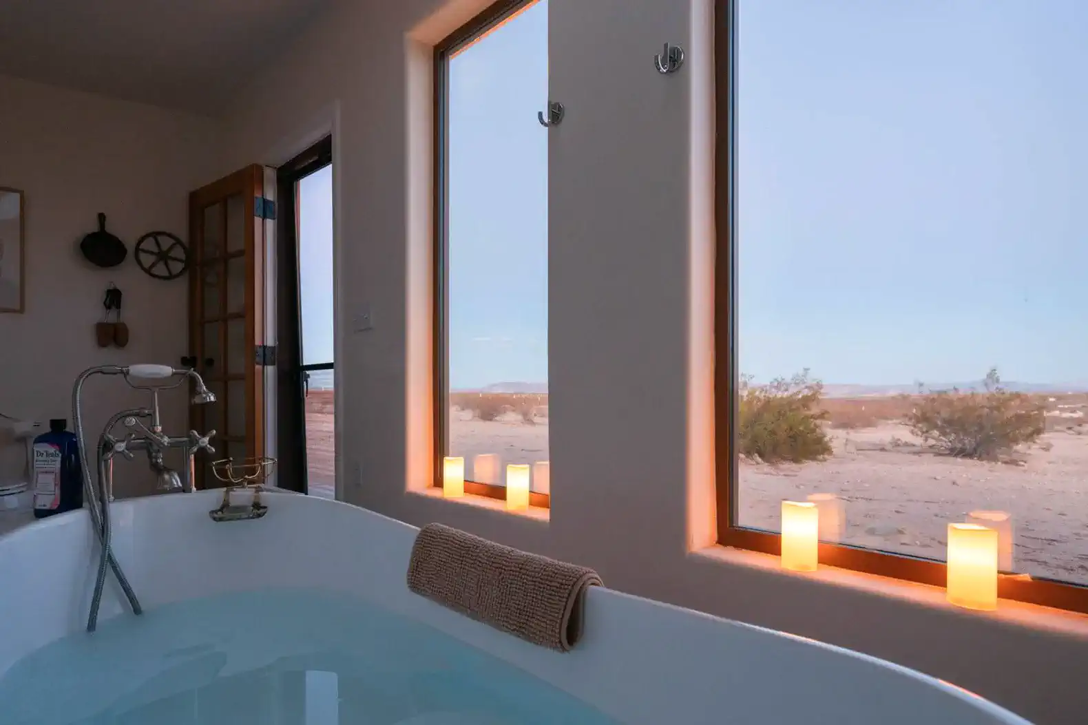 Bathtub with a view of the desert and candles illuminating the space