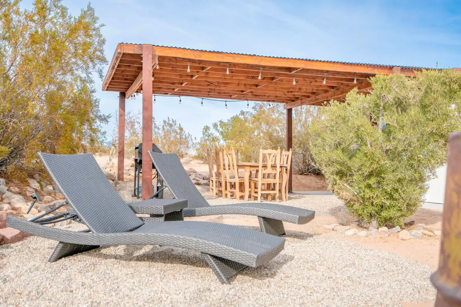 Outdoor seating area with loungers and dining table under a wooden pergola