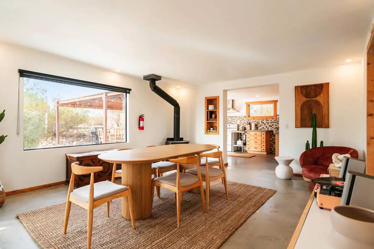 Bright dining area with a round wooden table and modern chairs, featuring a cozy stove