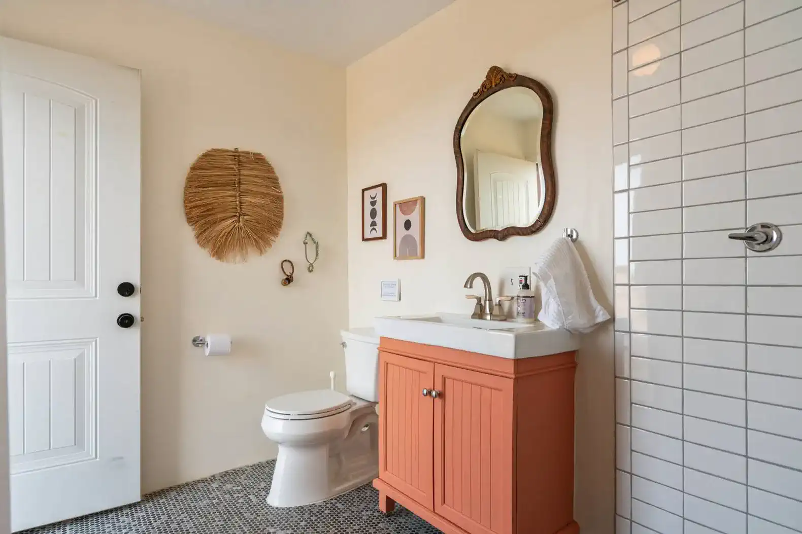 Stylish bathroom featuring a coral vanity, modern fixtures, and decorative wall art