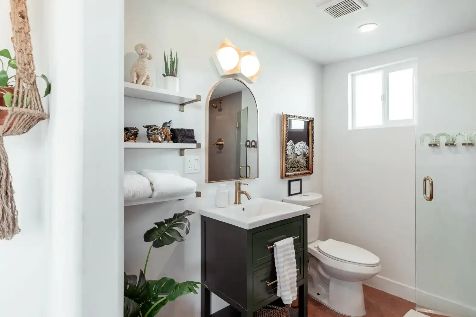 Modern bathroom featuring a green vanity, open shelving, and stylish lighting