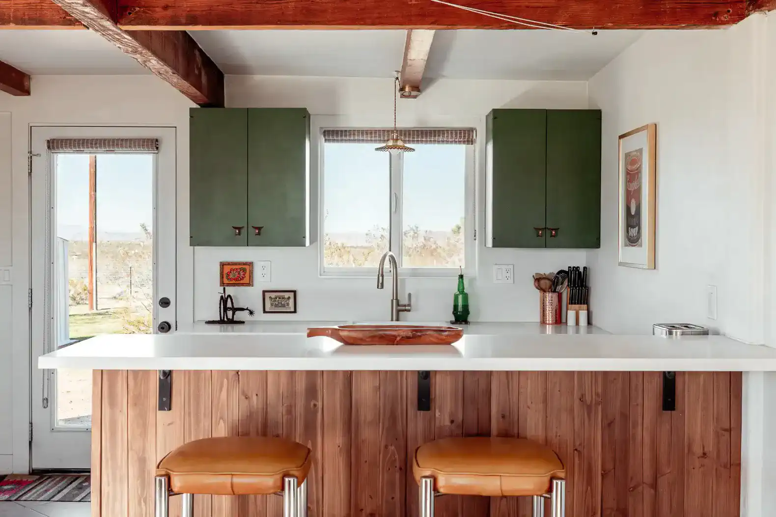 Modern kitchen with green cabinets, white countertop, and bar stools