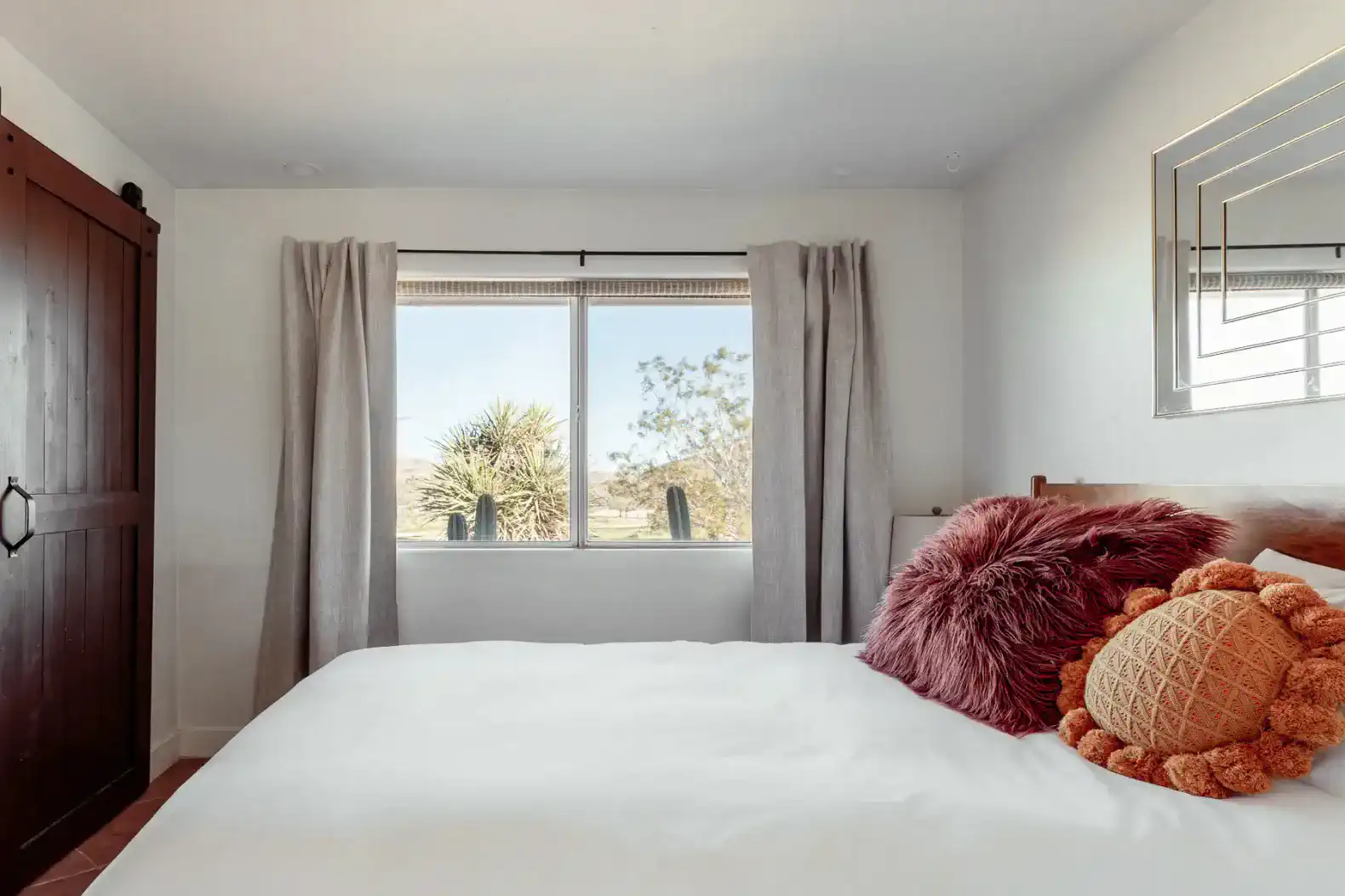 Cozy guest bedroom with a large window and decorative pillows