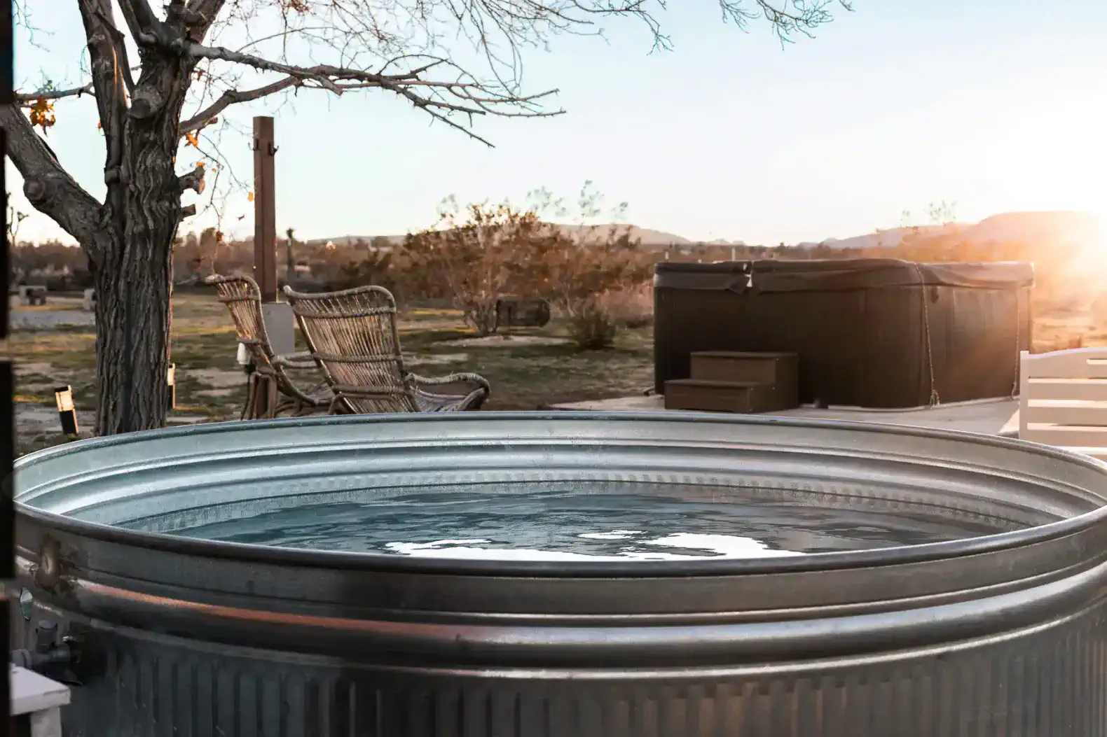 Hot tub with scenic sunset view and outdoor seating nearby