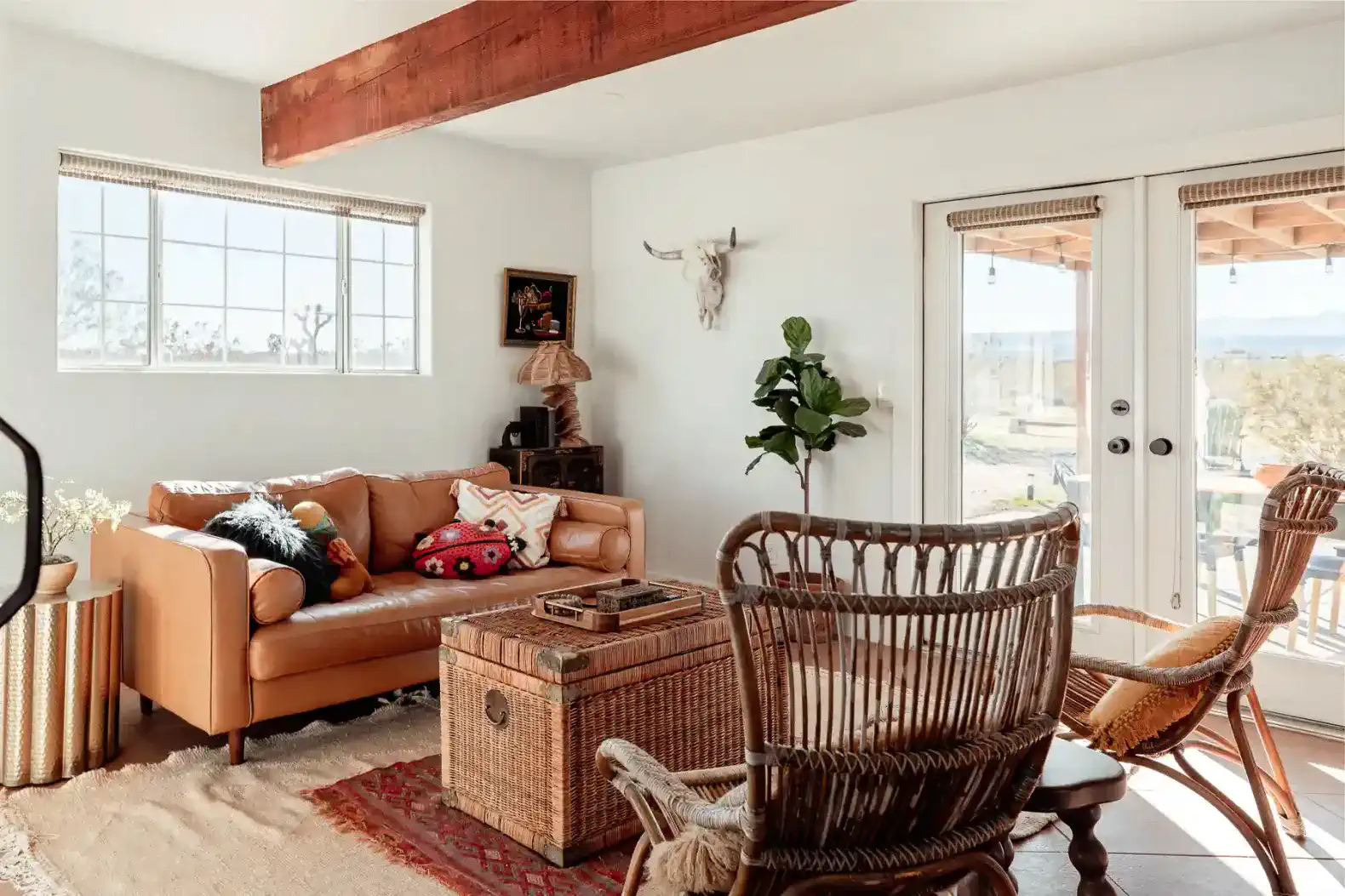 Cozy living room with leather sofa, decorative accents, and large windows opening to outdoor views