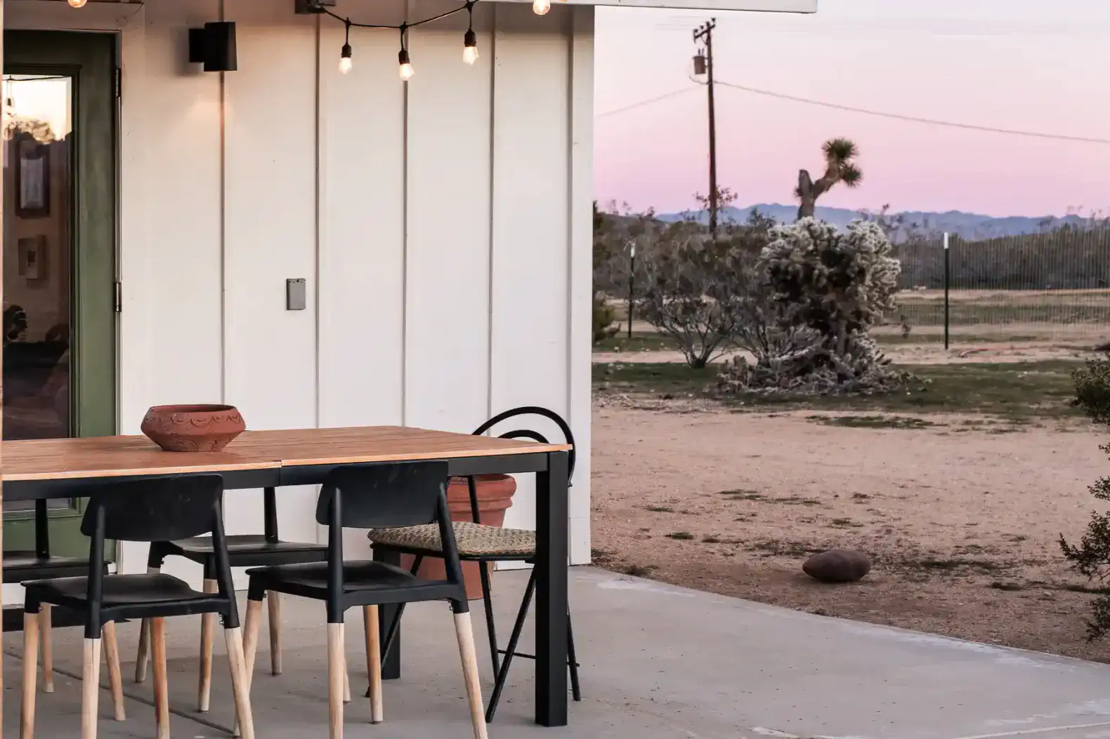 Outdoor dining area with a wooden table and chairs overlooking desert landscape