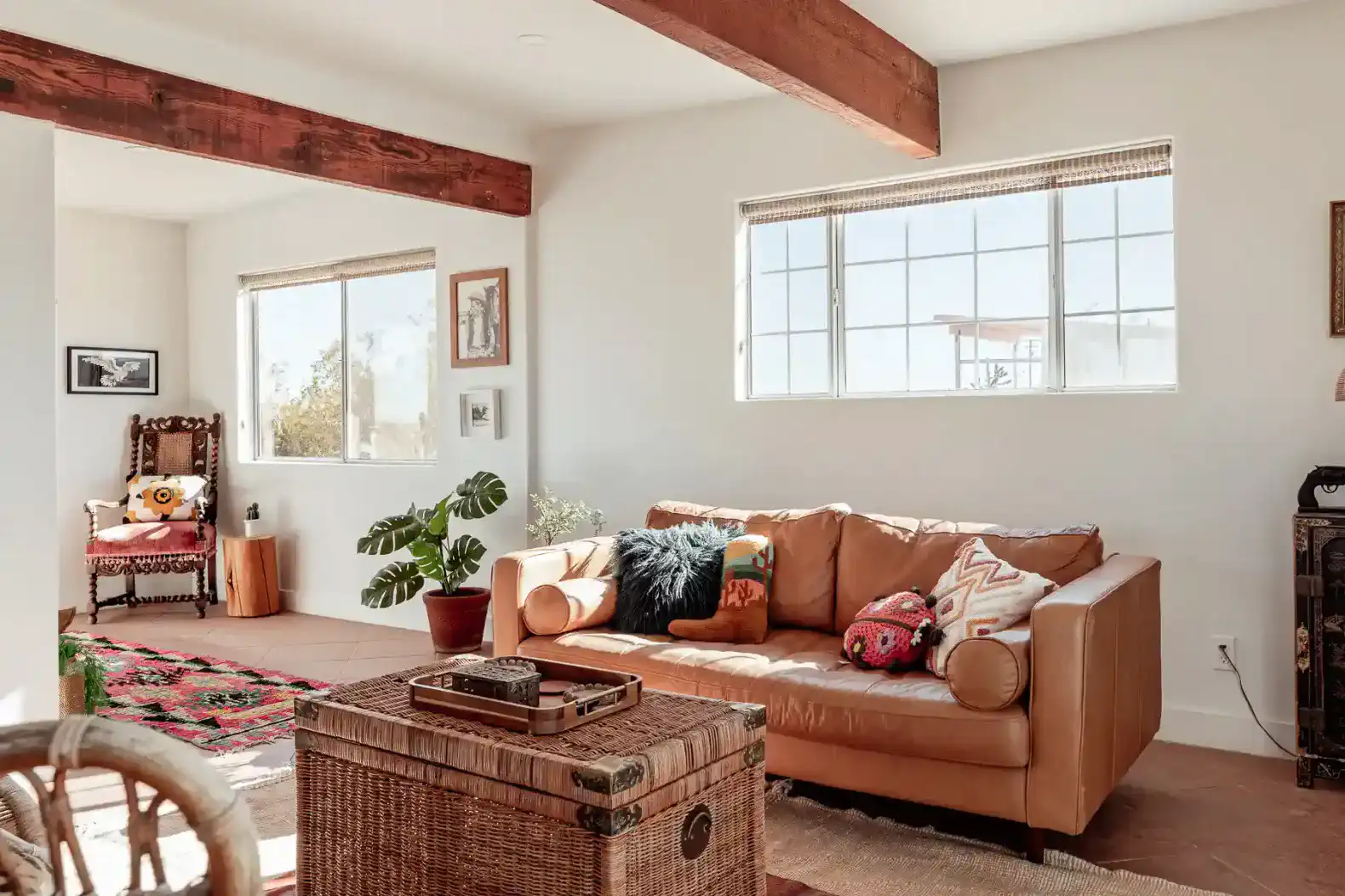 Cozy living room with leather sofa, decorative pillows, and large windows