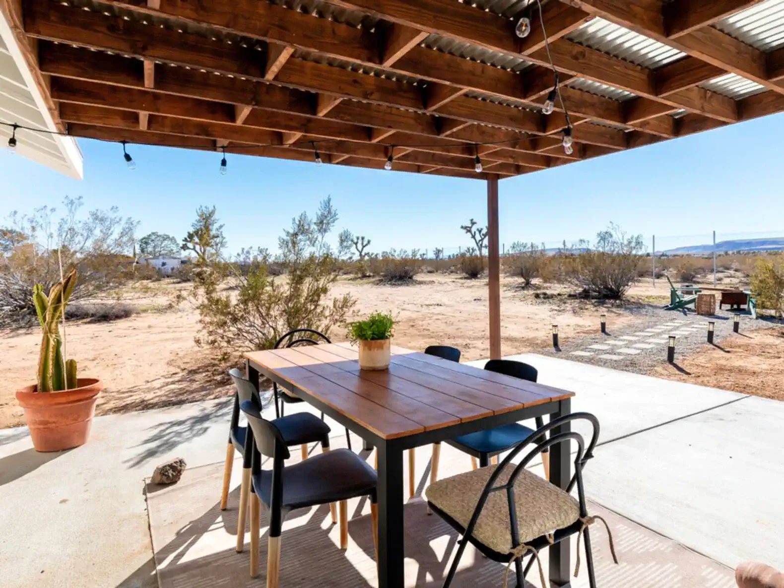 Outdoor dining area with a wooden table and chairs under a shaded patio