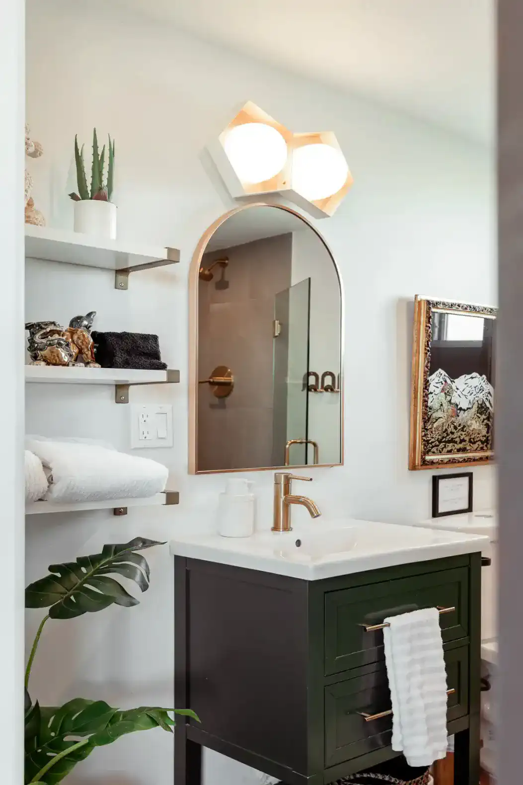 Modern bathroom with a stylish sink, gold fixtures, and decorative shelves