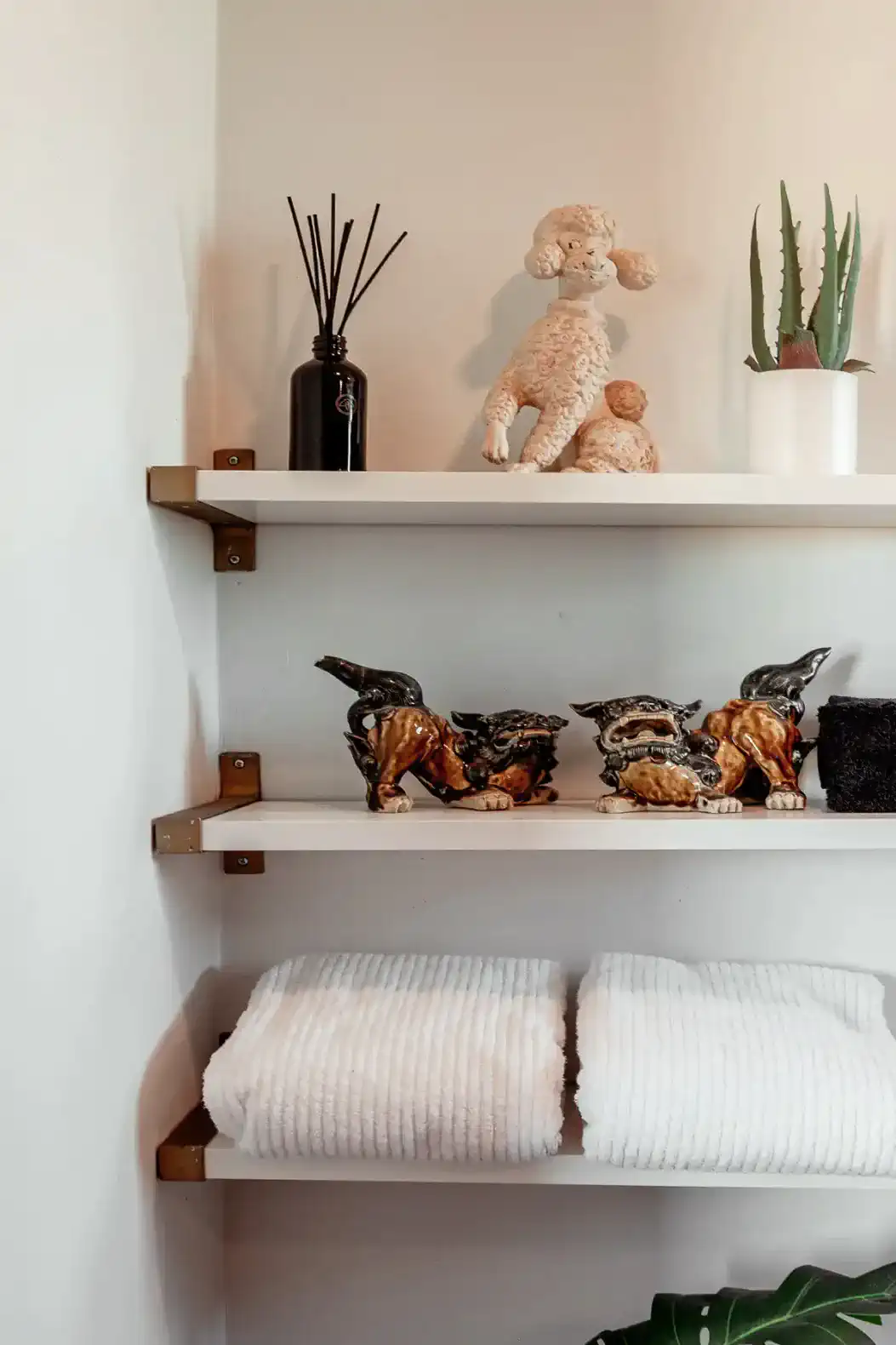 Decorative shelves with towels, figurines, and plants