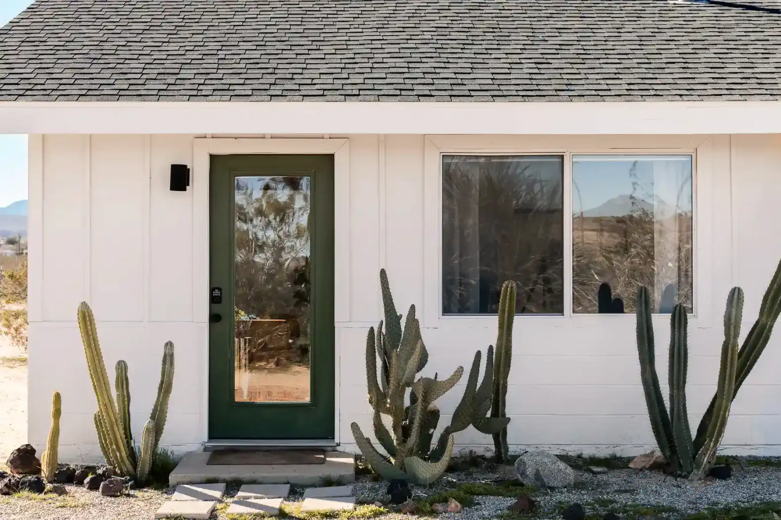 Front entrance with green door and desert landscaping featuring cacti