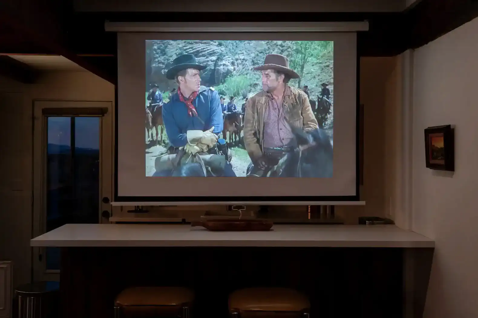 Home theater setup with a projector displaying a classic western film