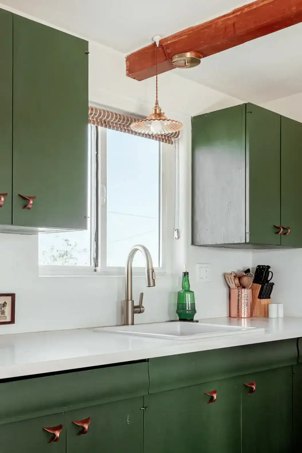 Modern kitchen with green cabinets, white countertops, and a window view