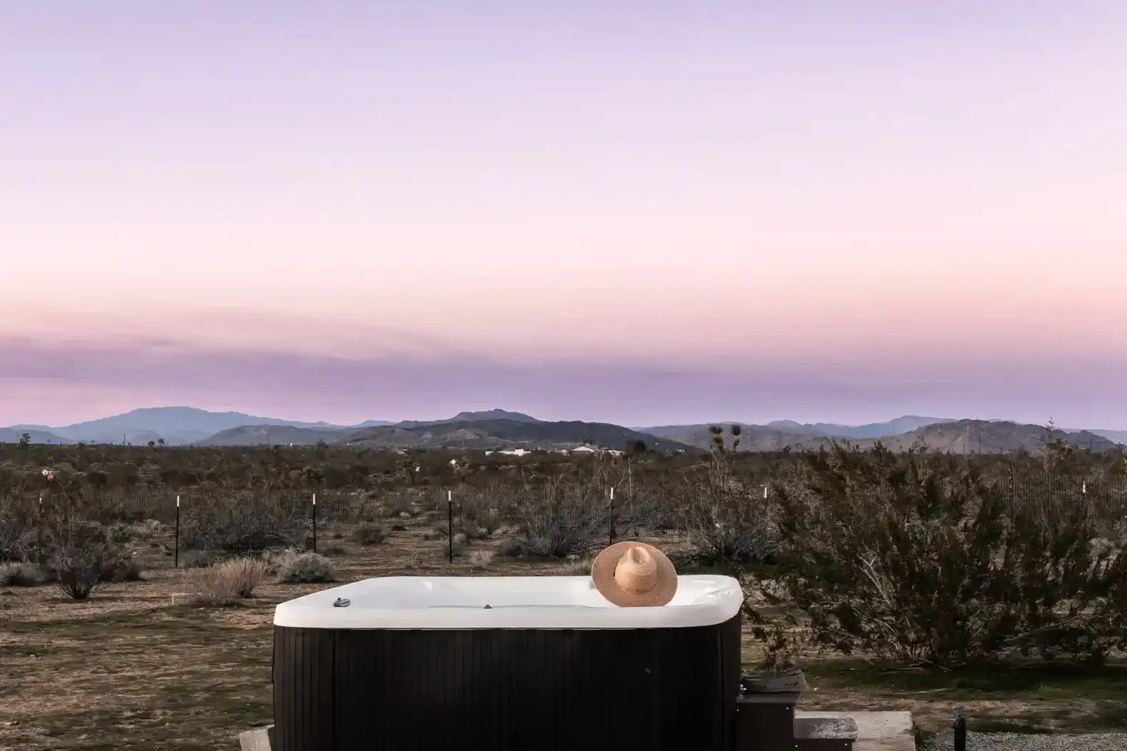 Hot tub with a straw hat against a desert sunset backdrop