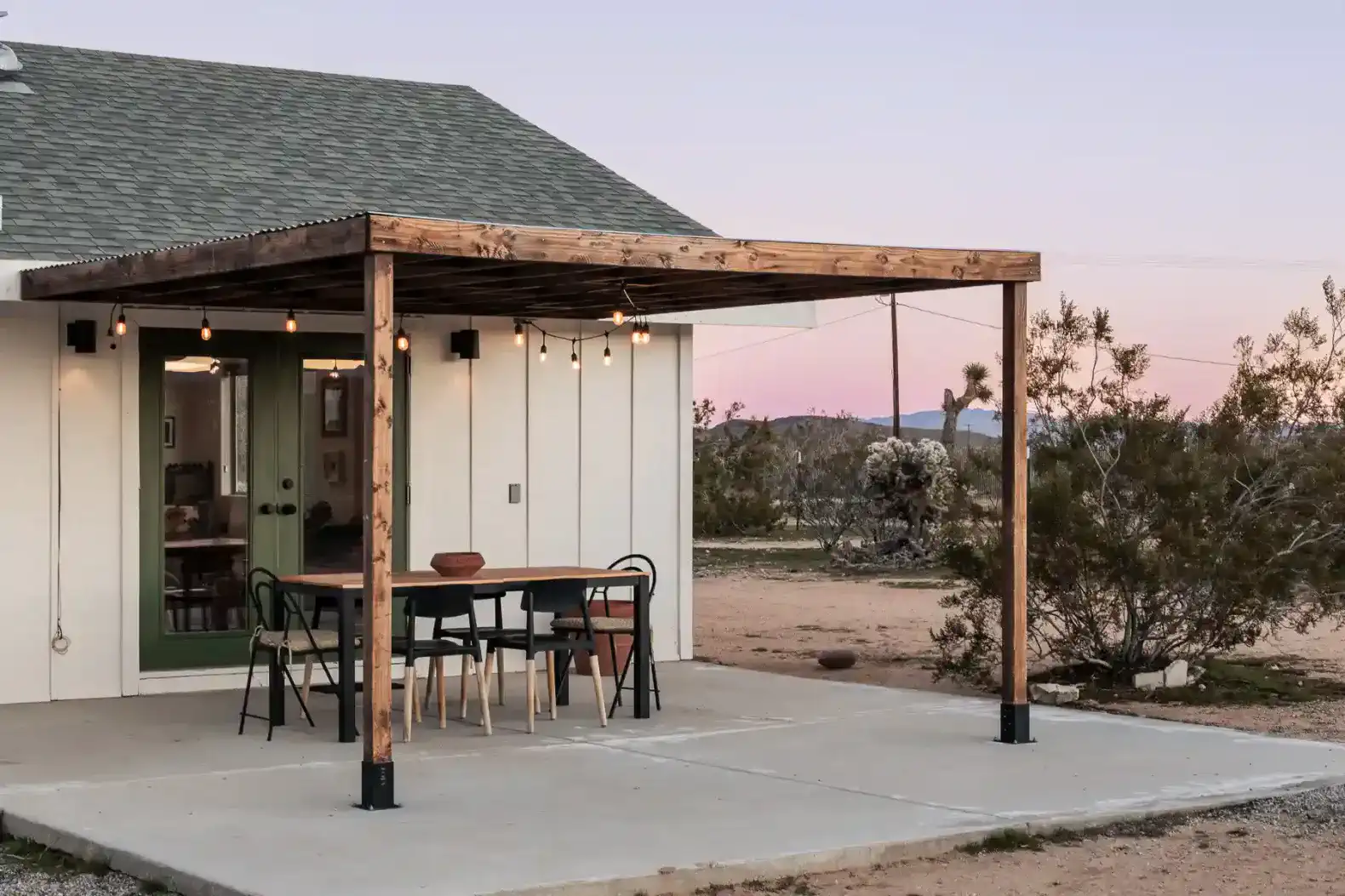 Covered outdoor dining area with string lights and desert landscape