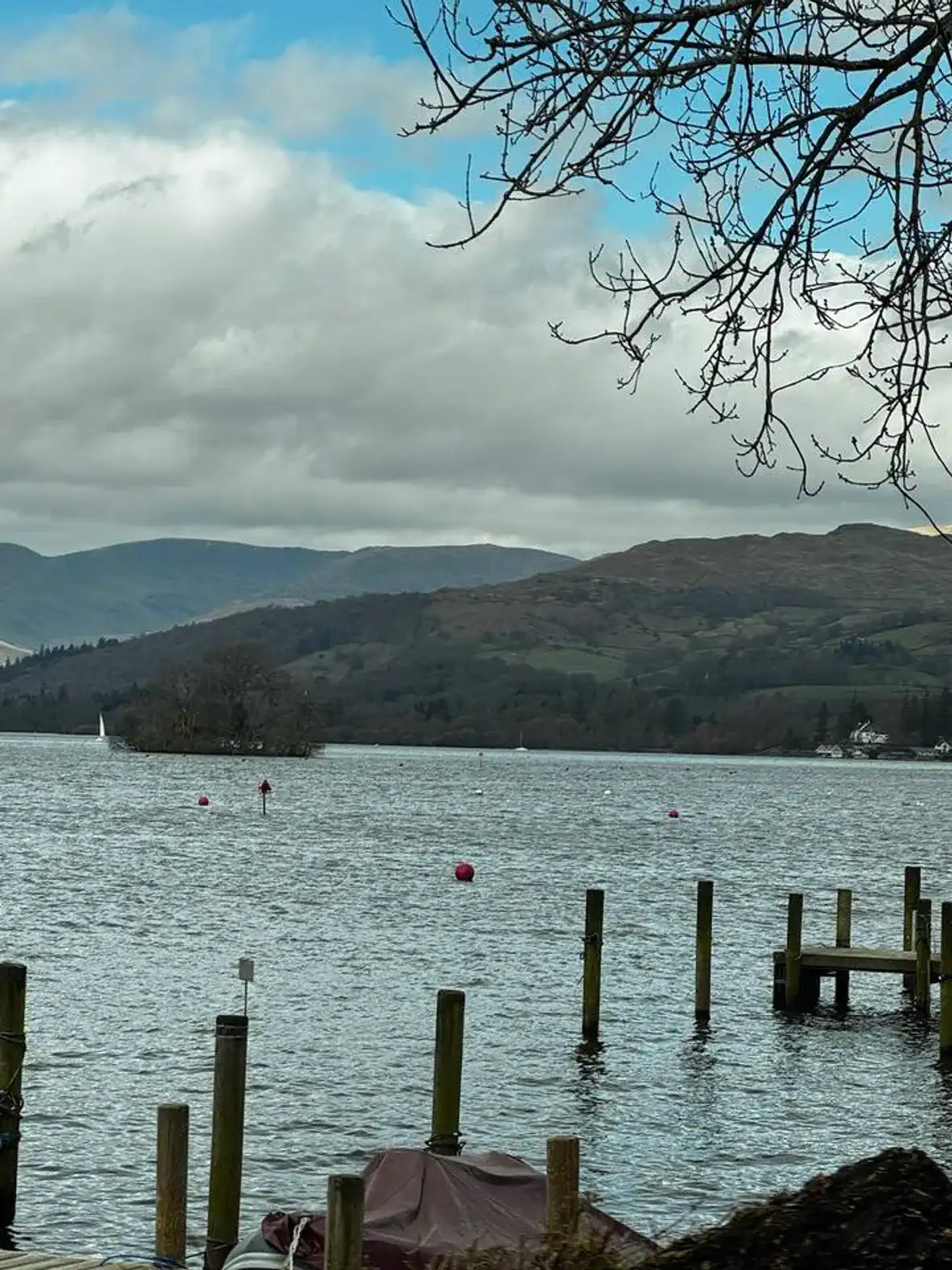 Scenic view of a lake surrounded by hills and cloudy skies