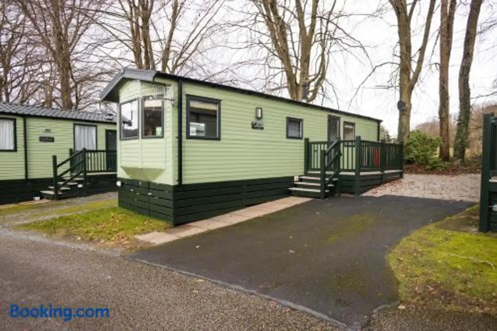 Exterior view of a green cabin with a deck surrounded by trees