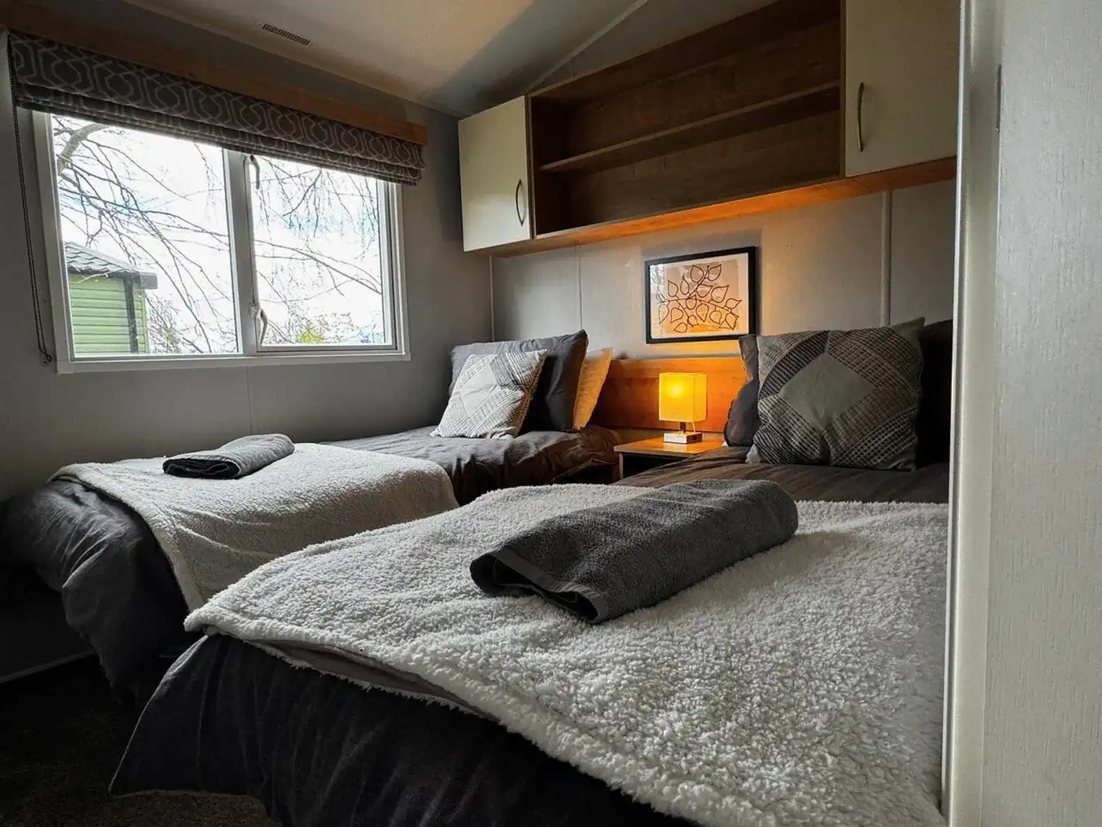 Cozy guest bedroom with two beds, soft linens, and natural light from the window