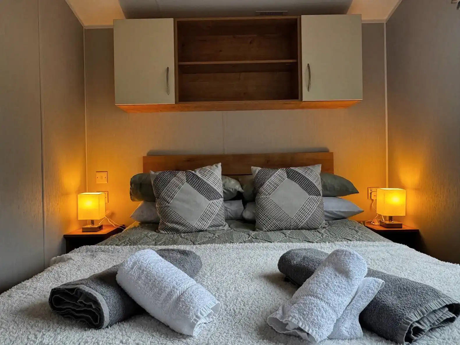 Cozy master bedroom with soft lighting and neatly arranged towels