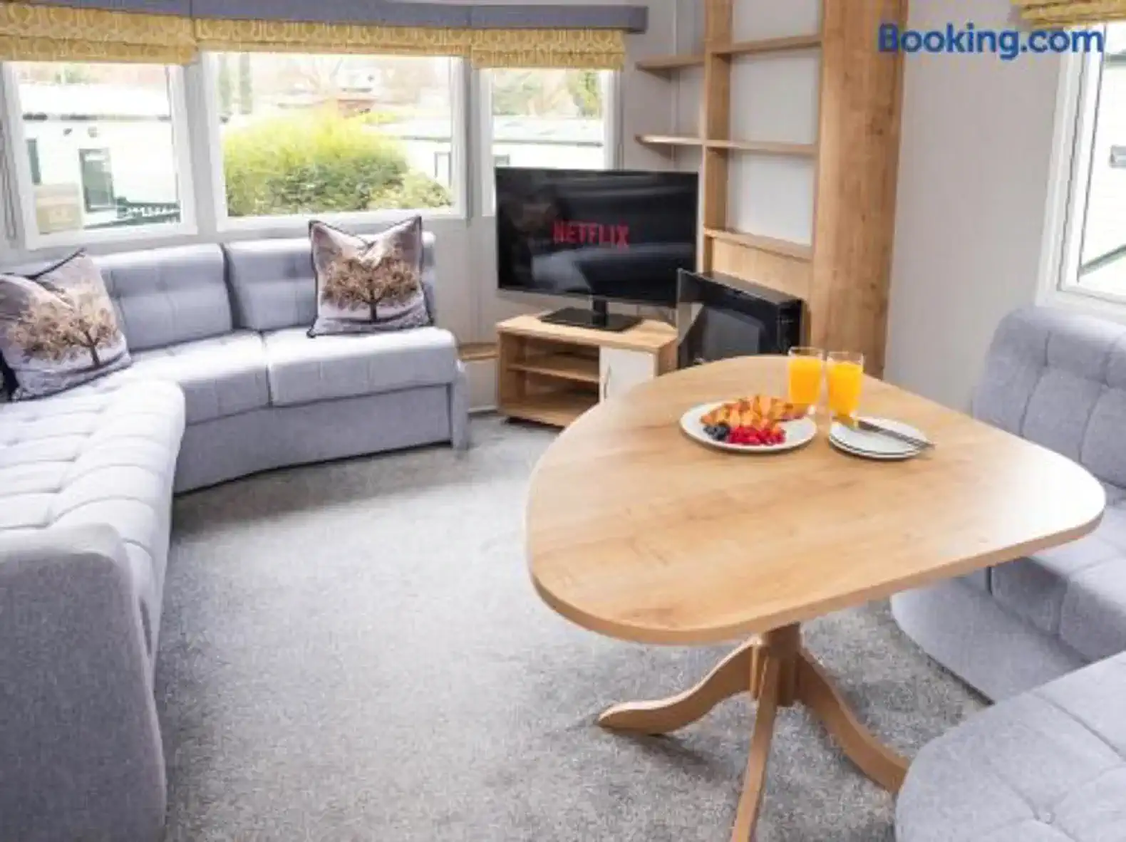 Cozy living room with gray sofas, a wooden table, and a TV displaying Netflix