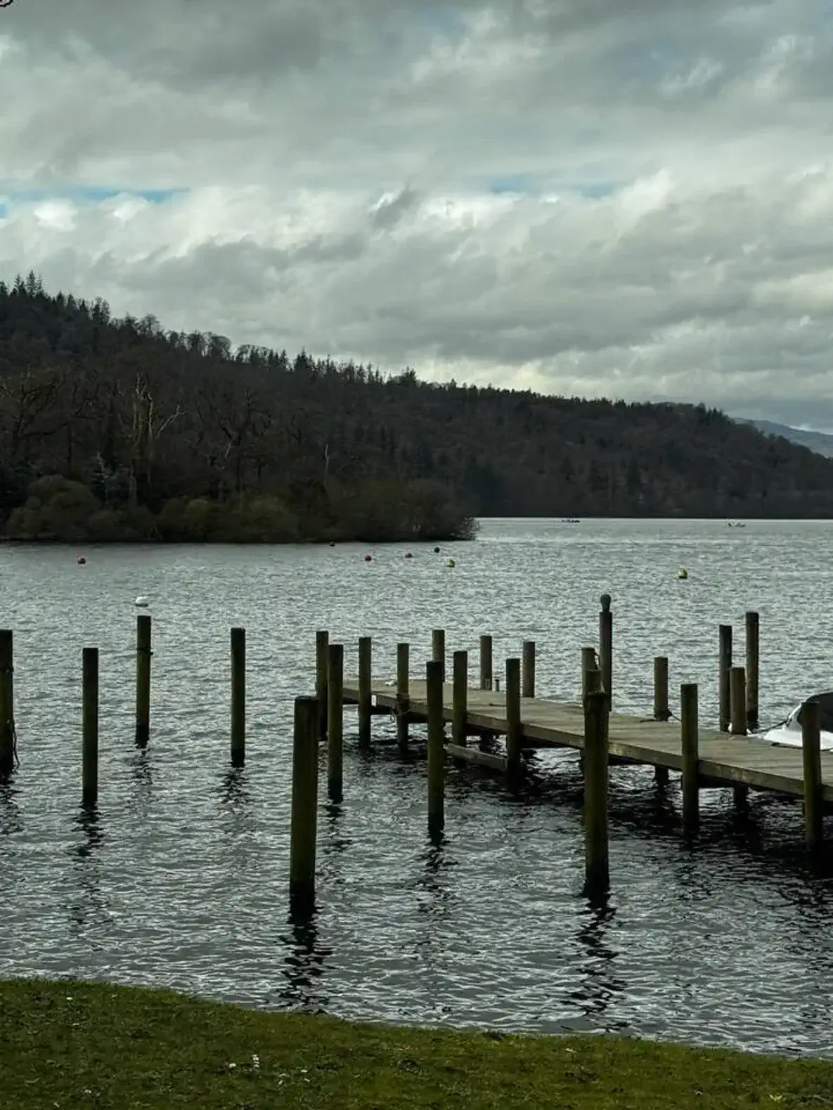 Scenic view of a wooden dock extending into a calm lake surrounded by trees and mountains