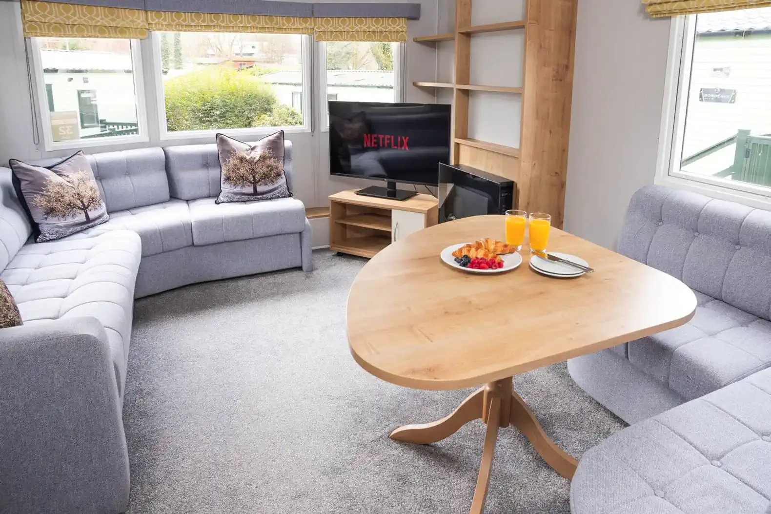 Cozy living area with gray sofas, a wooden table, and a TV displaying Netflix