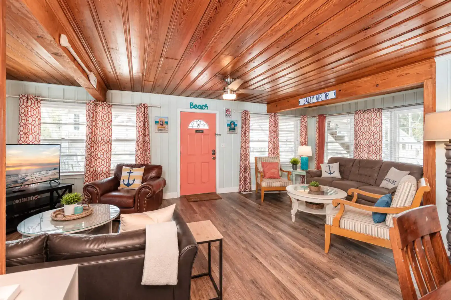 Cozy living room with nautical decor, wooden ceiling, and bright orange door
