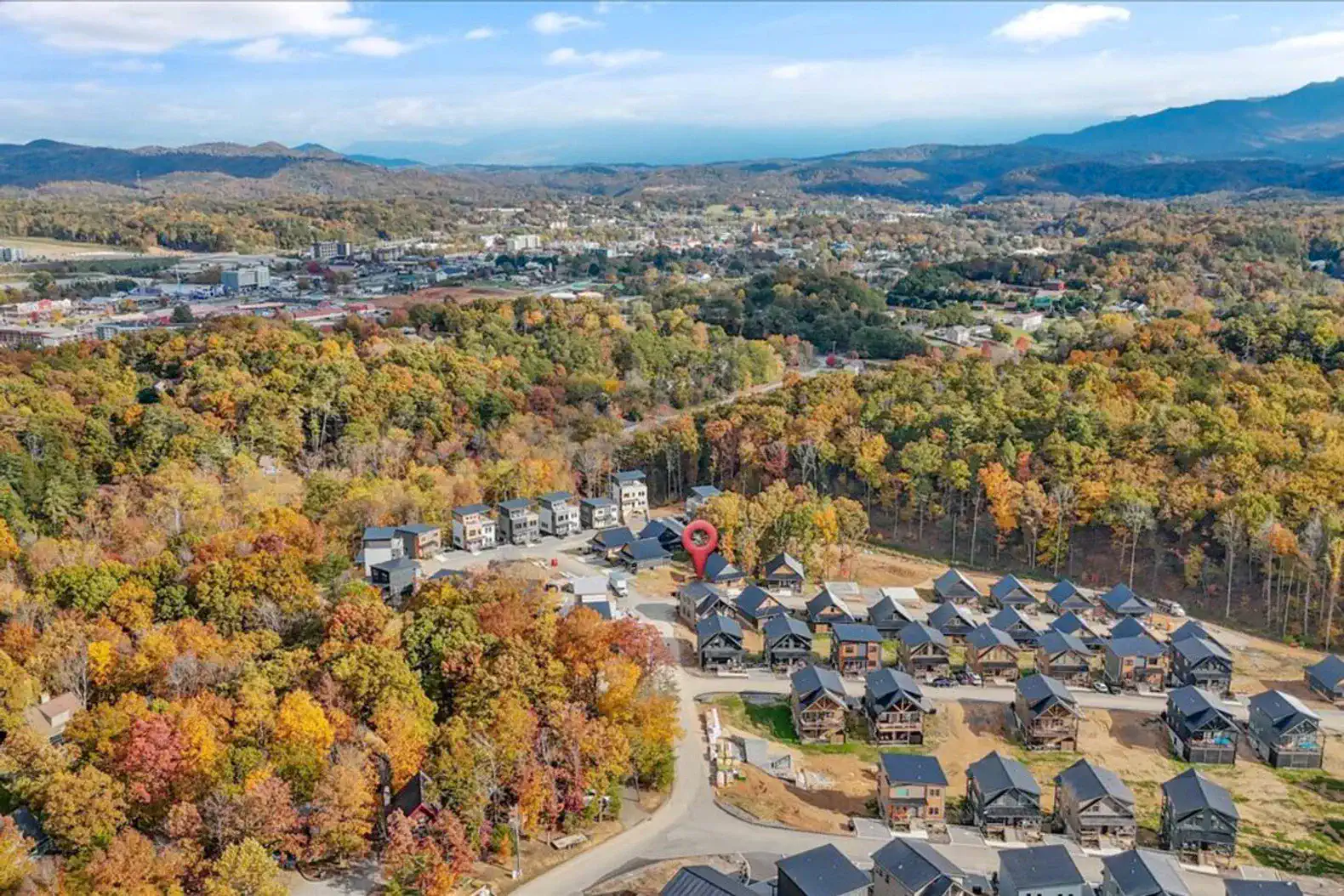 Aerial view of a wooded area with colorful autumn foliage and nearby cabins