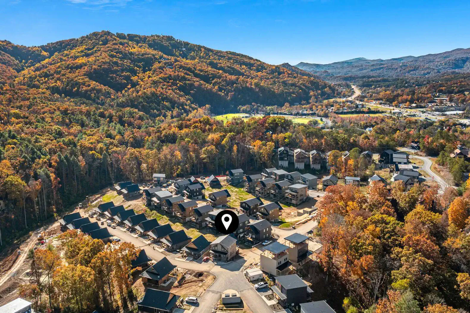 Aerial view of a neighborhood surrounded by autumn foliage and mountains