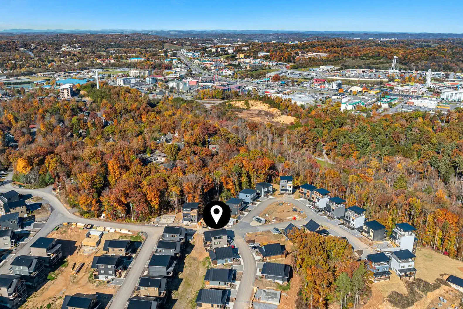 Aerial view of a neighborhood surrounded by autumn foliage and nearby commercial areas